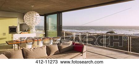 Stock Image - Modern living room and dining room overlooking ocean. Fotosearch