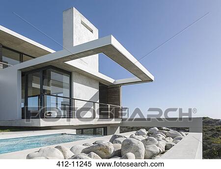 Stock Photography - Rocks along lap pool outside modern house. Fotosearch