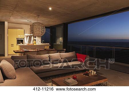 Stock Photograph - Sofa and dining table in modern living room overlooking ocean. Fotosearch
