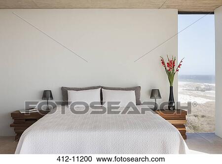 Vase Of Flowers Next To Bed In Bedroom With Ocean View Stock Image