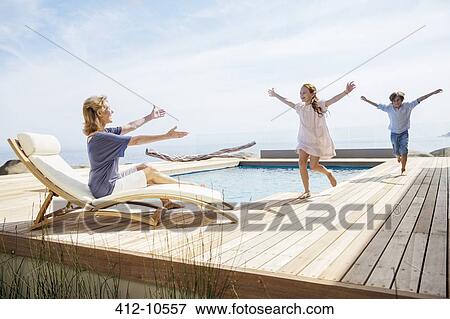 Stock Photo - Children running to grandmother by pool. Fotosearch
