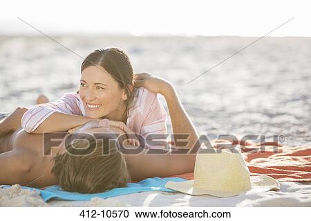 Stock Image - Couple relaxing together on beach. Fotosearch