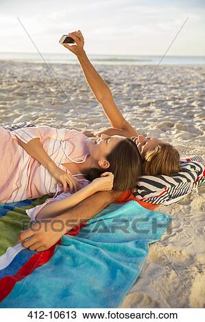 Couple taking pictures together on beach View Large Photo Image Stock Image - Couple taking pictures together on beach. Fotosearch