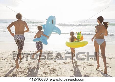Stock Image - Family playing together on beach. Fotosearch