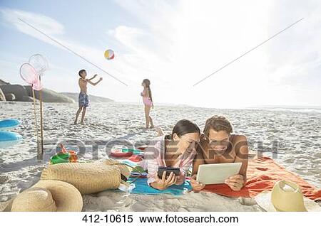 Stock Photography - Family relaxing together on beach. Fotosearch