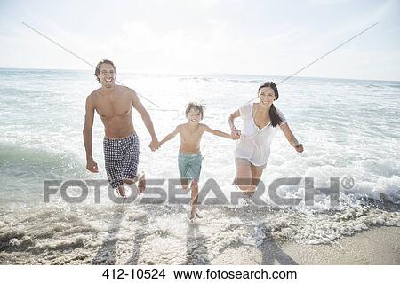 Picture - Family running in surf on beach. Fotosearch