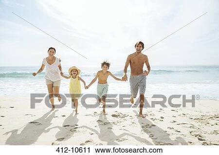 Stock Image - Family running together on beach. Fotosearch