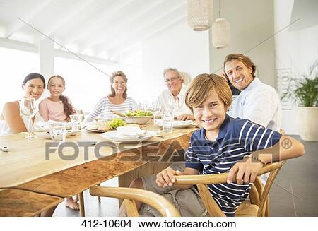 Picture - Family smiling together at table. Fotosearch
