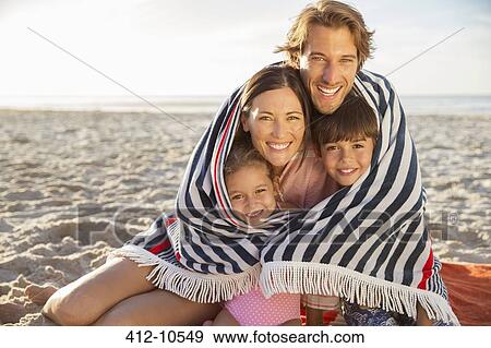 Stock Photo - Family wrapped in blanket on beach. Fotosearch