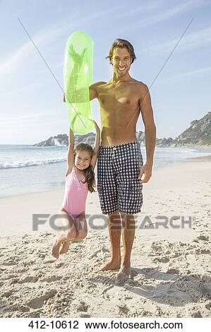 Stock Image - Father and daughter playing on beach. Fotosearch