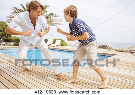 Stock Photo - Father and son playing by pool. Fotosearch