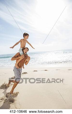 Stock Photograph - Father and son playing on beach. Fotosearch
