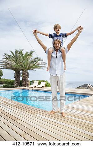 Father carrying son on shoulders at poolside View Large Photo Image Stock Image - Father carrying son on shoulders at poolside. Fotosearch