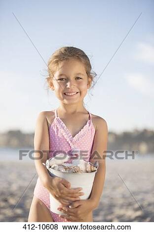 Girl holding bucket of shells on beach View Large Photo Image Stock Photo - Girl holding bucket of shells on beach. Fotosearch