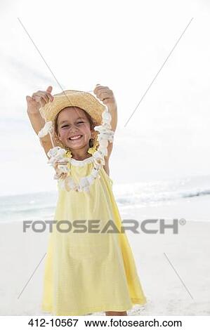 Stock Photo - Girl playing with seashells on beach. Fotosearch