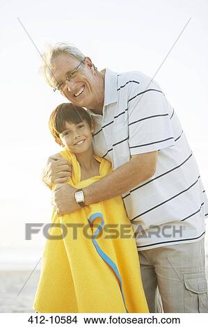 Picture - Grandfather hugging grandson on beach. Fotosearch