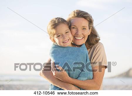 Stock Photograph - Grandmother and granddaughter hugging on beach. Fotosearch
