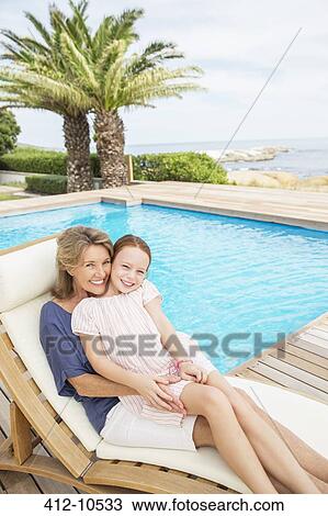 Grandmother and granddaughter relaxing at poolside View Large Photo Image Stock Image - Grandmother and granddaughter relaxing at poolside. Fotosearch