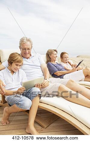 Stock Photo - Grandparents and grandchildren using digital tablets at poolside. Fotosearch