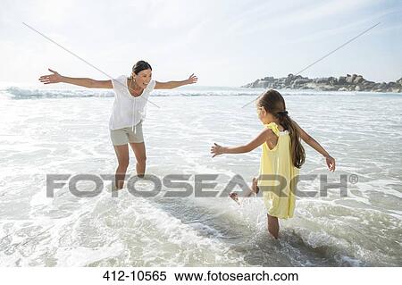 Mother and daughter playing in surf at beach View Large Photo Image Stock Photography - Mother and daughter playing in surf at beach. Fotosearch