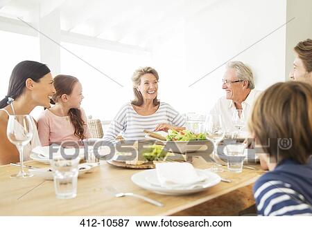 Stock Photo - Multi-generation family eating together at table. Fotosearch