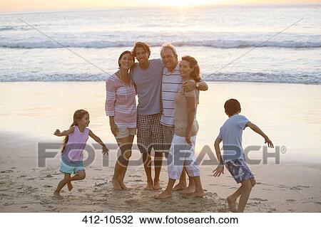 Stock Image - Multi-generation family hugging on beach. Fotosearch