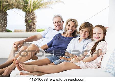Stock Photo - Older couple and grandchildren relaxing on sofa. Fotosearch