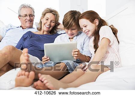 Older couple and grandchildren using digital tablet View Large Photo Image Stock Photograph - Older couple and grandchildren using digital tablet. Fotosearch