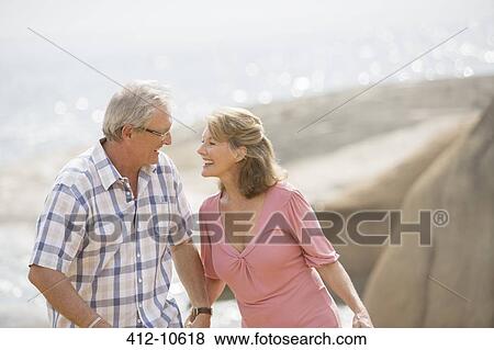 Stock Photo - Older couple holding hands on beach. Fotosearch