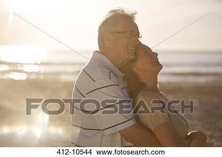 Picture - Older couple hugging on beach. Fotosearch
