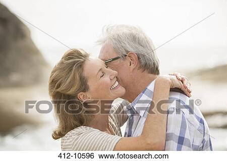 Stock Photograph - Older couple kissing on beach. Fotosearch