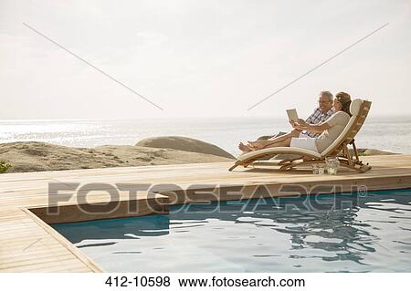 Stock Photo - Older couple relaxing by pool. Fotosearch