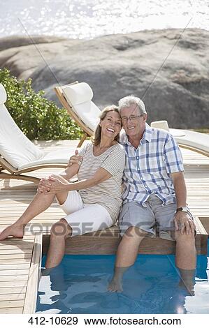 Stock Photo - Older couple relaxing by swimming pool. Fotosearch