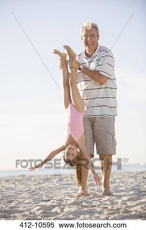 Stock Photography - Older man playing with granddaughter on beach. Fotosearch
