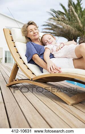 Stock Image - Older woman and granddaughter relaxing in lawn chair. Fotosearch