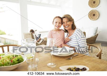 Picture - Older woman and granddaughter smiling at table. Fotosearch