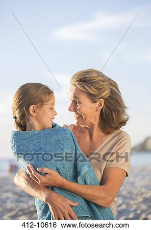 Stock Photograph - Older woman holding granddaughter on beach. Fotosearch
