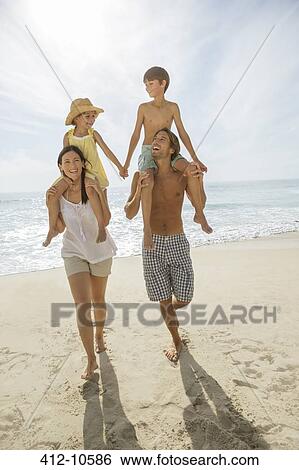Parents carrying children on shoulders at beach View Large Photo Image Stock Photograph - Parents carrying children on shoulders at beach. Fotosearch
