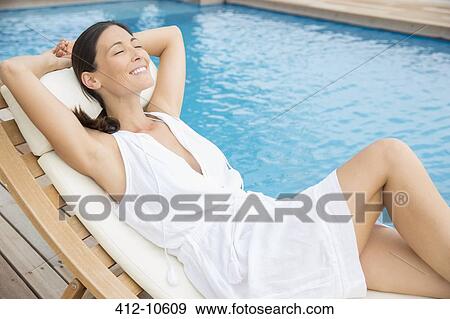 Stock Photo - Woman relaxing by pool. Fotosearch