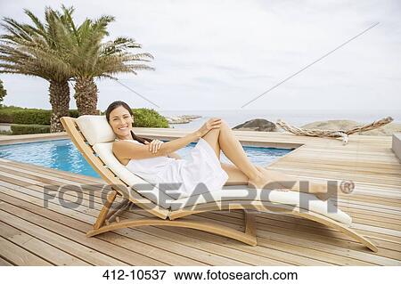 Woman relaxing in lounge chair at poolside View Large Photo Image Stock Photo - Woman relaxing in lounge chair at poolside. Fotosearch