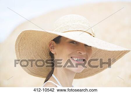 Stock Image - Woman wearing straw hat outdoors. Fotosearch