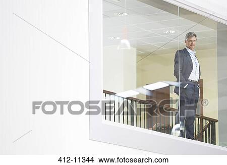 Picture - Businessman looking out glass window. Fotosearch