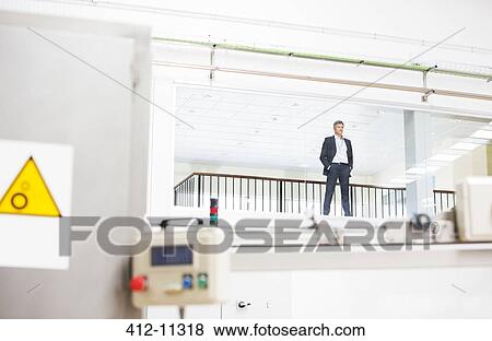 Businessman looking out observation window in factory View Large Photo Image Stock Photo - Businessman looking out observation window in factory. Fotosearch