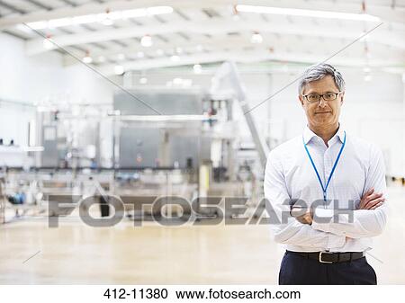Stock Image - Businessman smiling in factory. Fotosearch