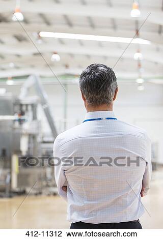 Businessman standing in factory View Large Photo Image Stock Image - Businessman standing in factory. Fotosearch