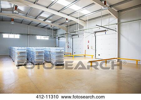 Stock Image - Pallets of water bottles in empty warehouse. Fotosearch