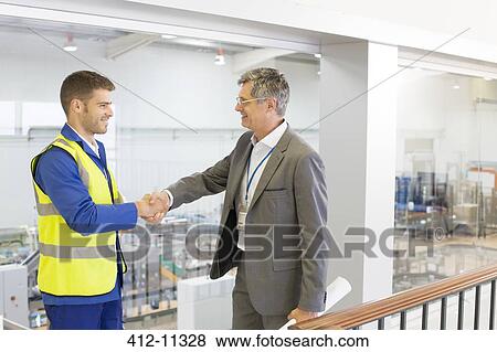 Stock Photo - Supervisor and worker shaking hands in factory. Fotosearch