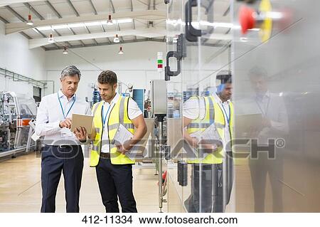 Supervisor and worker using digital tablet in factory View Large Photo Image Picture - Supervisor and worker using digital tablet in factory. Fotosearch