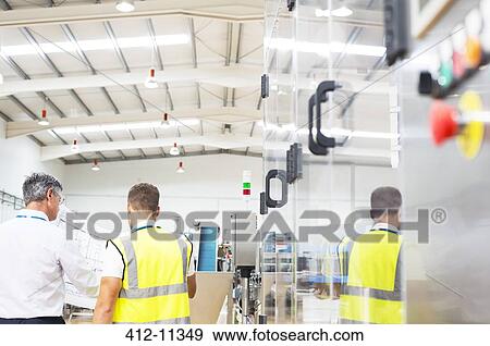 Stock Photo - Supervisor and worker viewing blueprints in factory. Fotosearch