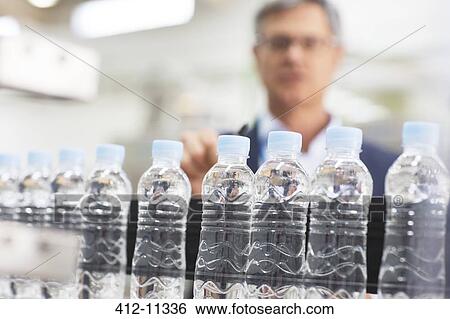 Supervisor examining bottles in factory View Large Photo Image Stock Photograph - Supervisor examining bottles in factory. Fotosearch